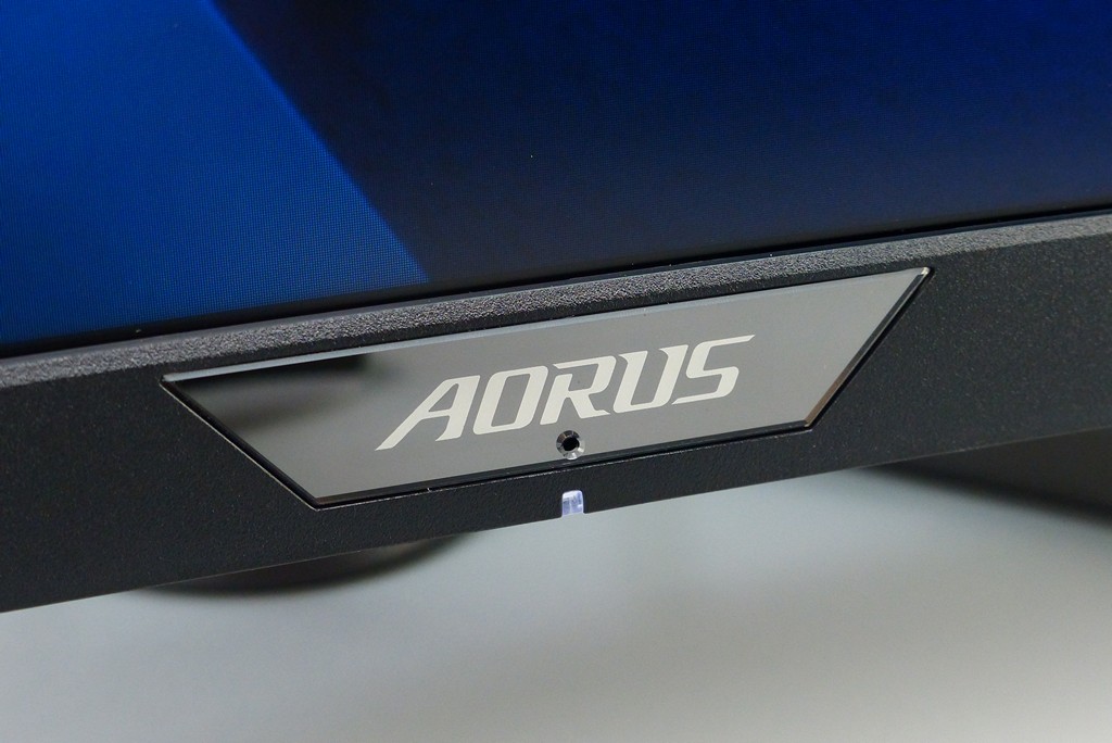 ▲ 螢幕本體正面下方設計有 AORUS 壓克力名牌與電源指示燈（待機：橘色、開機：白色），其中壓克力開設 1 個小孔，應為麥克風主動式抗噪 ACN 2.0 收音之處。