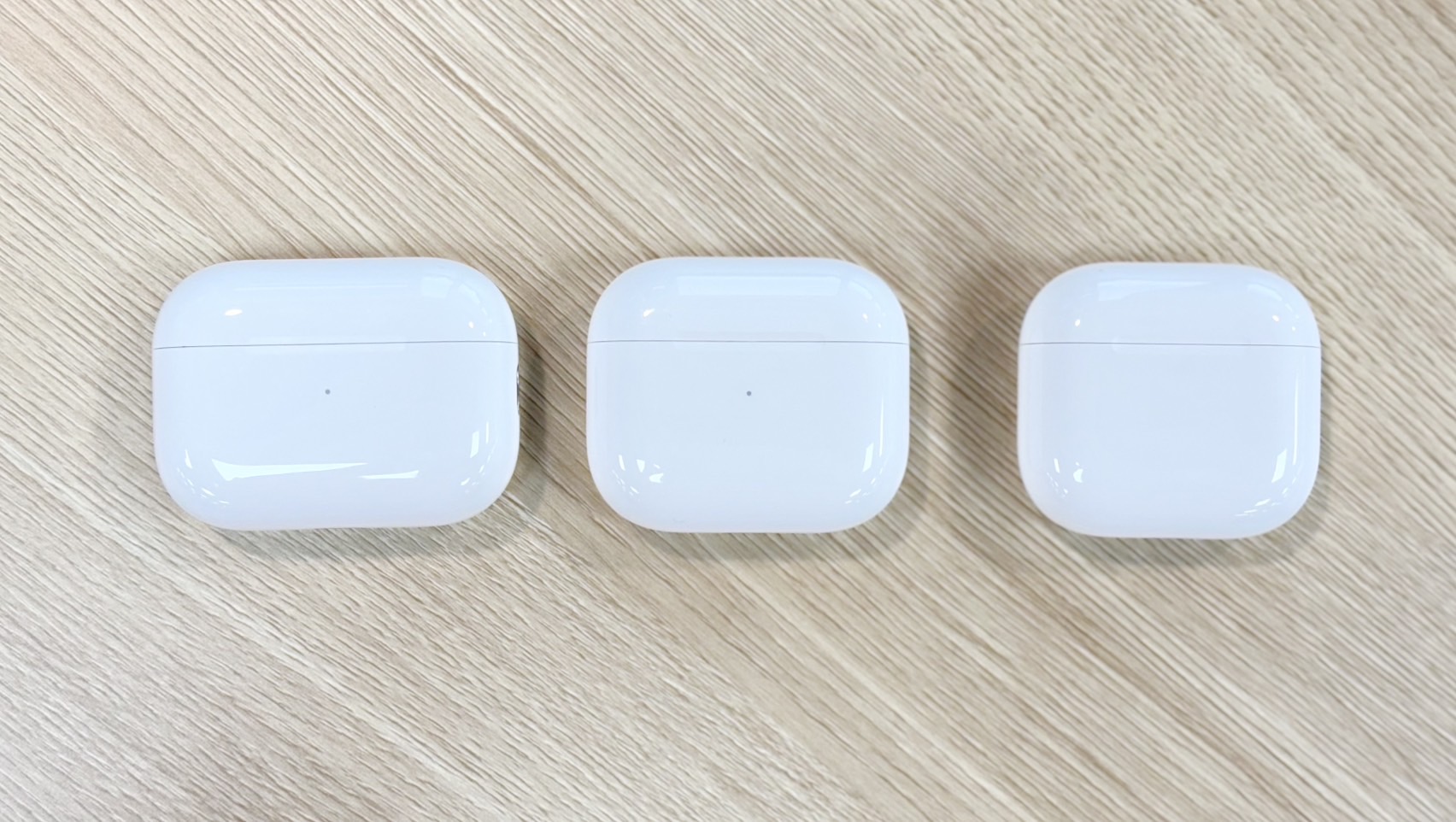 把 AirPods 4（右）、AirPods 3（中）、AirPods Pro 2（左）放在一起，就能看出充電盒外型上的大小差異。