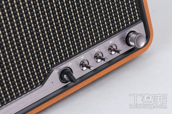 編織網罩與金屬控制鈕木質箱體上點綴著編織格柵，鋁質操控面板整合了細緻的金屬旋鈕與撥桿。